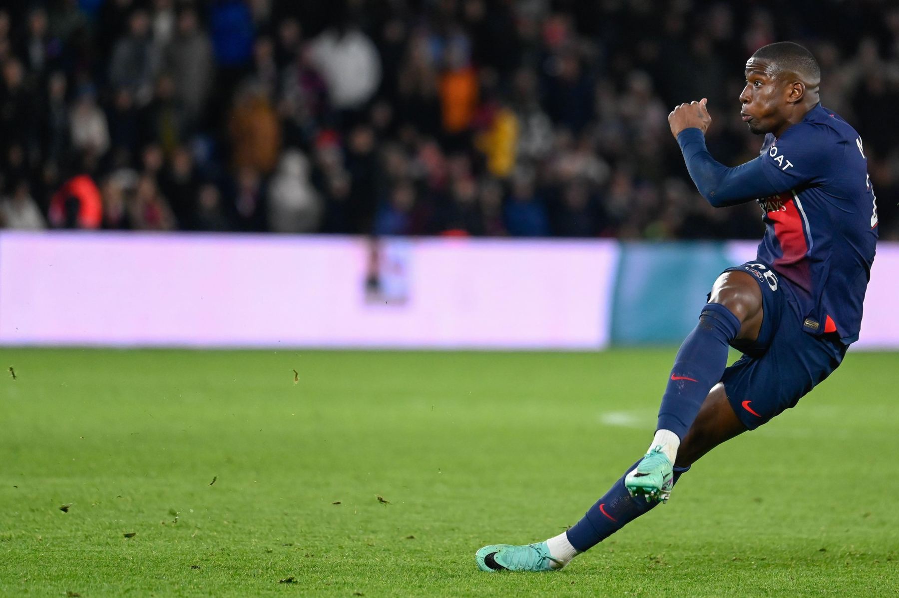 Footballer striking the ball under the stadium lights